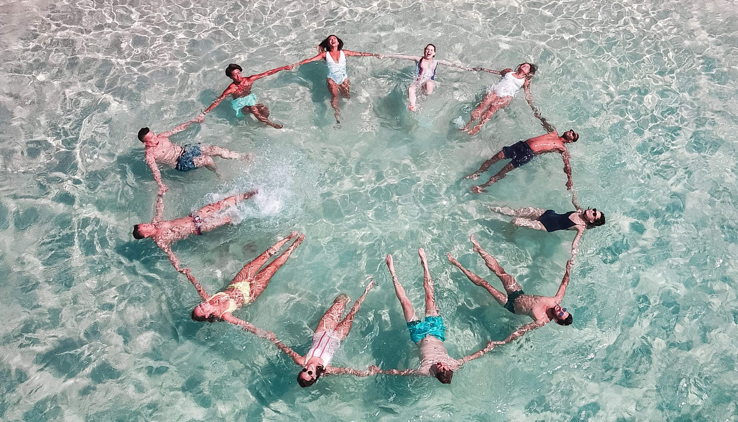 group holding hands and forming a circle in the water