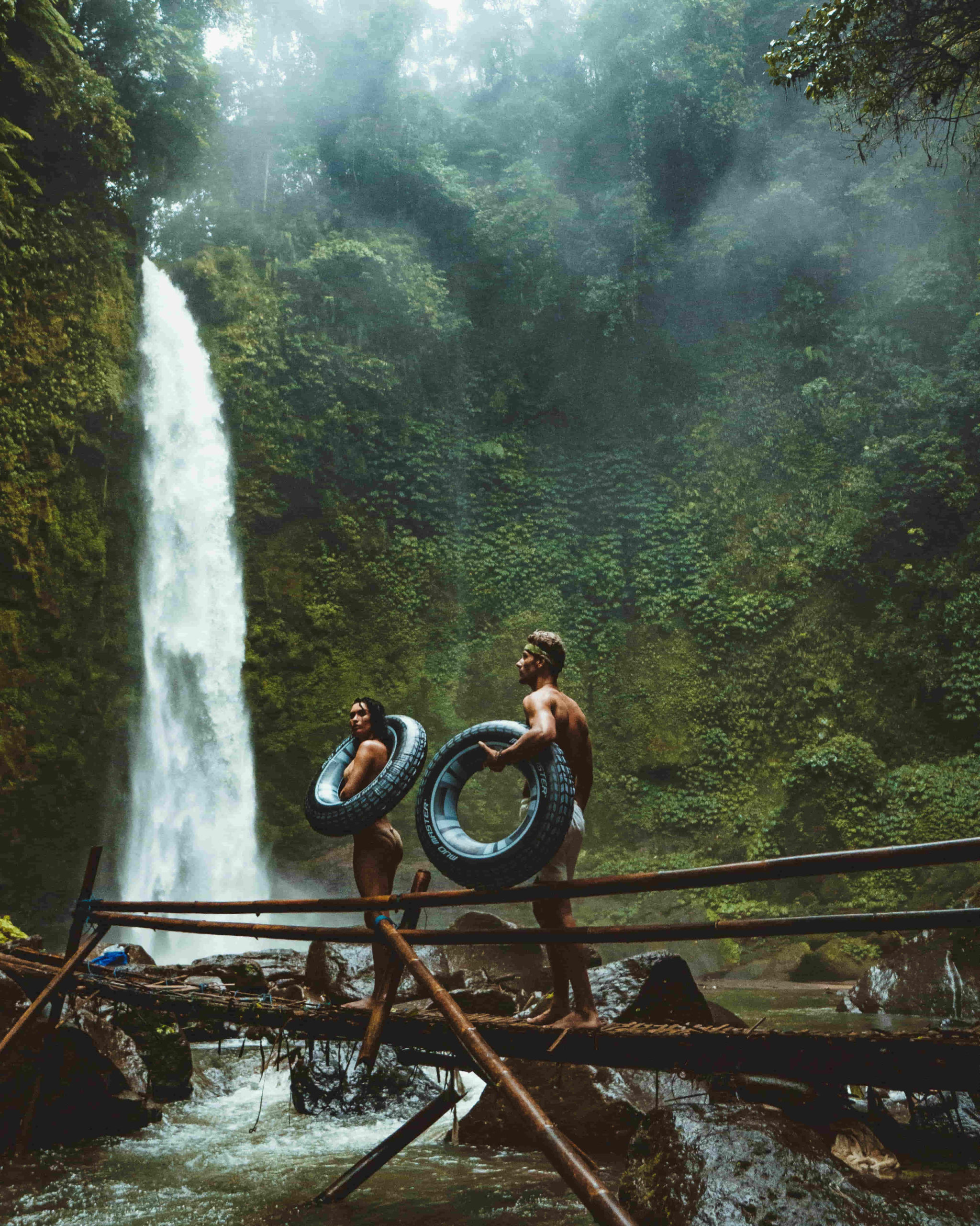young couple going for a swim at a waterfall in a jungle